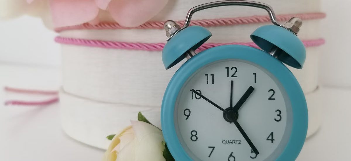 Charming blue analog alarm clock against a background of delicate flowers.