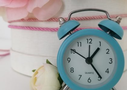 Charming blue analog alarm clock against a background of delicate flowers.